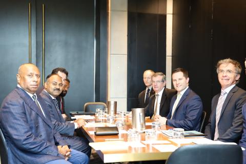 Group photo of delegates from both Governments in the meeting room.